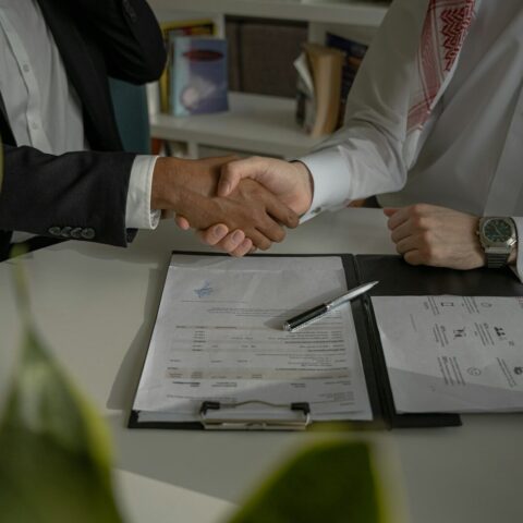 two people shaking hands over a piece of paper