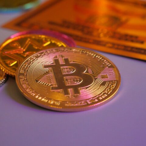 Golden bitcoin coin with other coins and card.