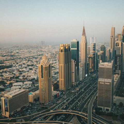 Modern skyscrapers line a busy highway in a sprawling city.