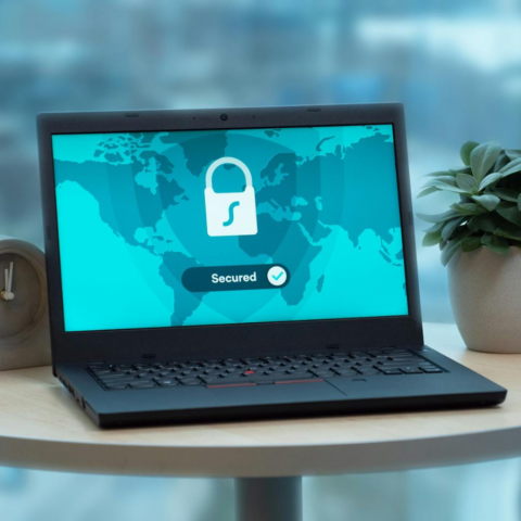 Safeguarding Personal Data in the Digital - Laptop displaying a security lock icon on a table with a potted plant and clock.