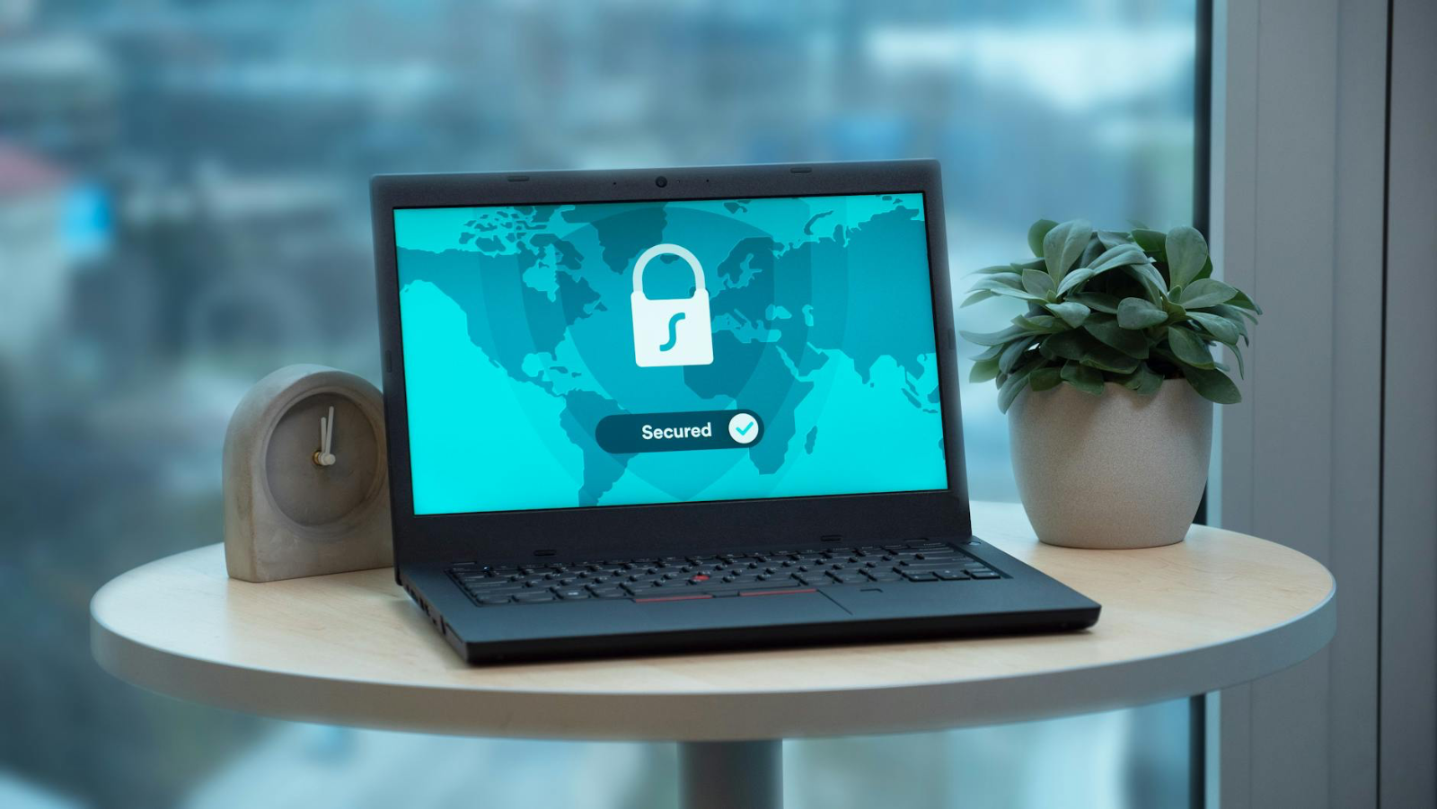 Safeguarding Personal Data in the Digital - Laptop displaying a security lock icon on a table with a potted plant and clock.