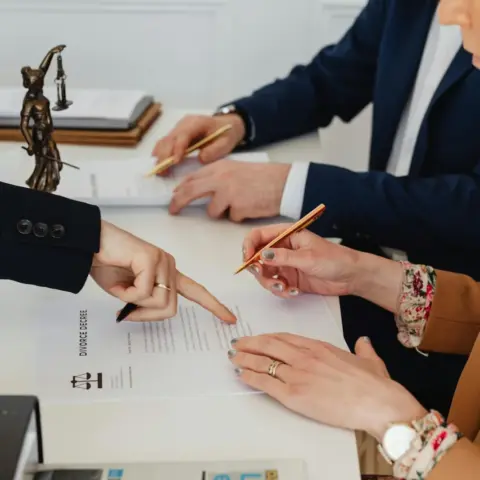 The New UAE Civil Transactions Law - Hands signing a divorce decree, with a justice statue nearby, symbolizing legal proceedi